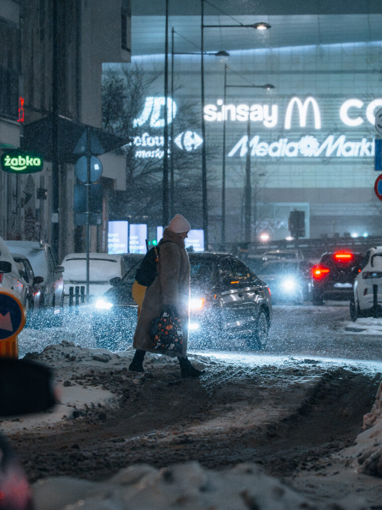 A woman crossing a street in front of a car. 