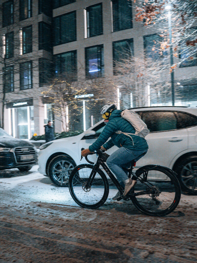 A guy riding a bike during snowfall.