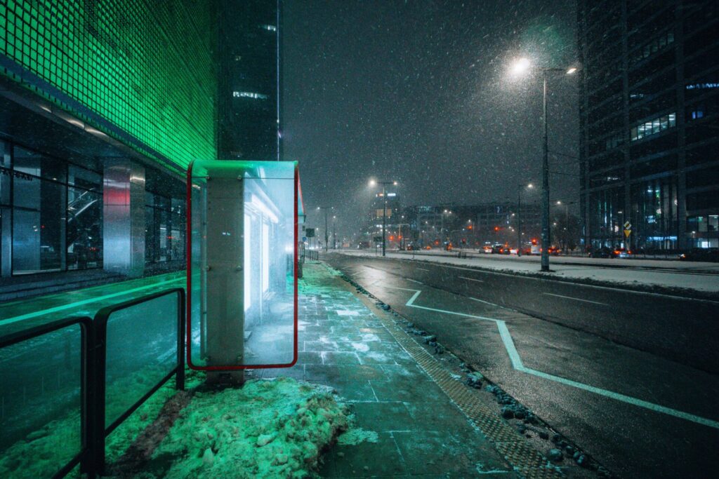 A nicely highlighted bus stop during snowfall.