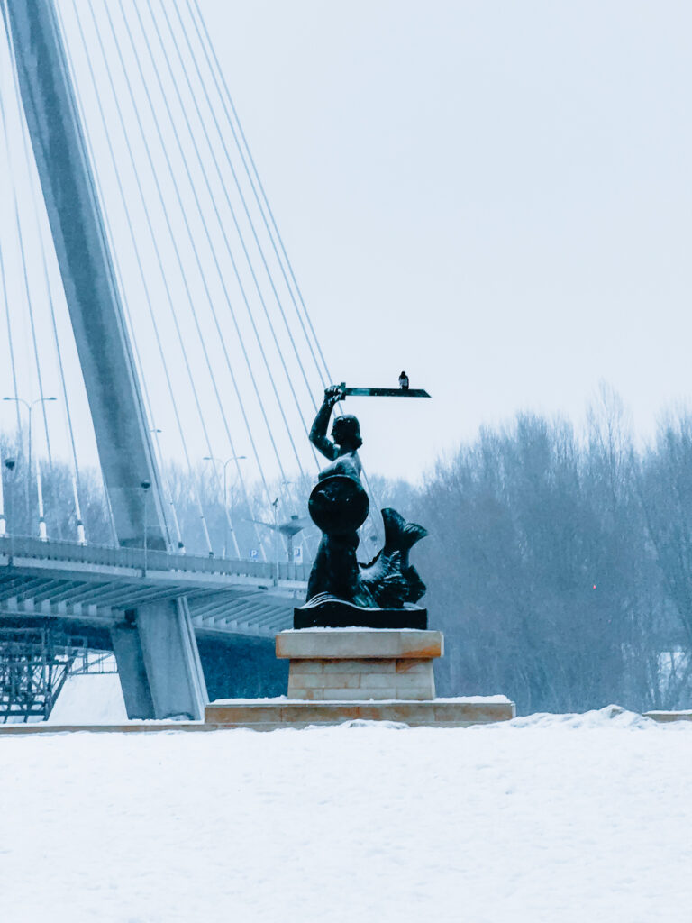 Syrenka Warszawska covered in snow, and the bridge in the back.