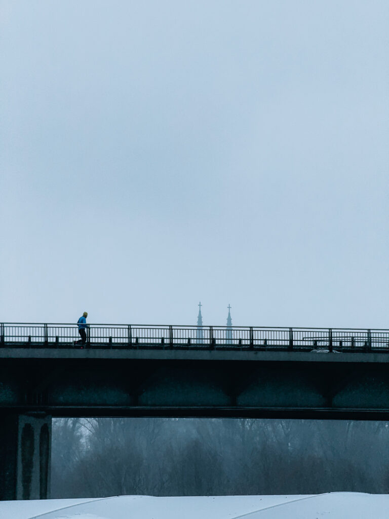 A minimalist shot of a runner on a bridge taken with the SANDMARC Telephoto Tetraprism lens.