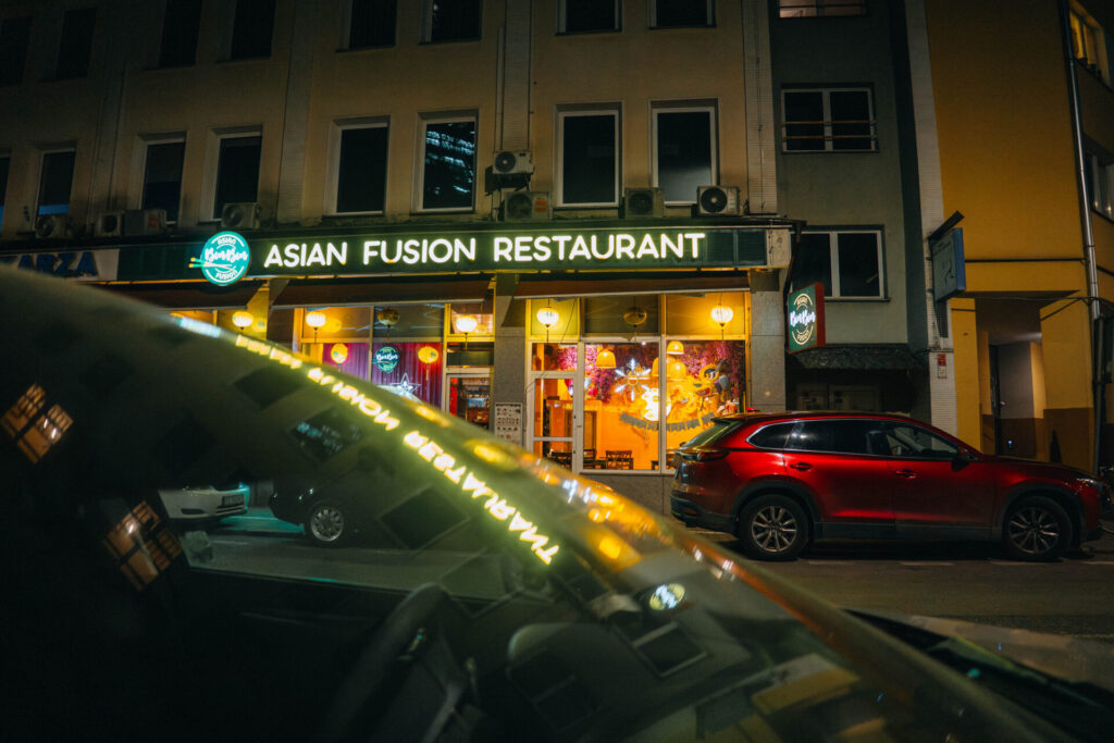 Asian Fusion Restaurant reflected in a car's window.