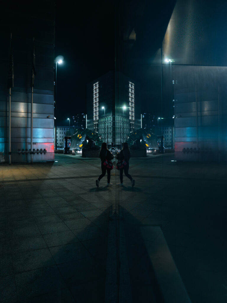 A perfect reflection of a fit lady walking on the sidewalk. Taken with Sigma 15mm F1.4 DC.