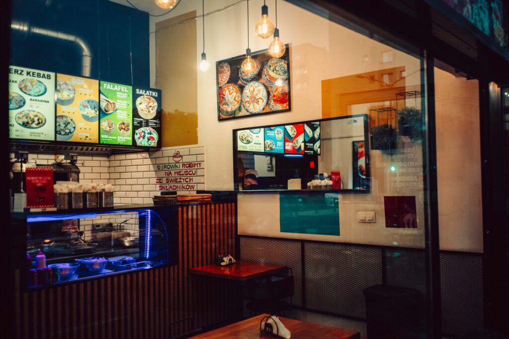 Local kebab store front. A lot of lights and ads.